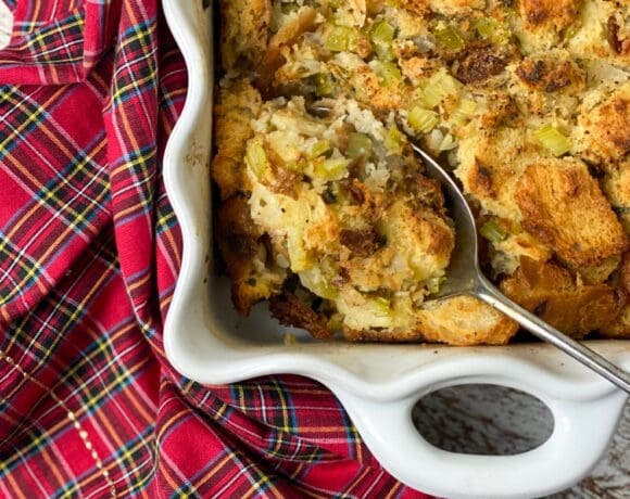 Old fashioned Thanksgiving dressing in a white pan with a spoon and a plaid napkin