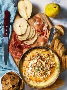 baked brie with fig jam and almonds and pears and prosciouto