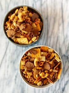 two bowls of chex mix on a marble counter