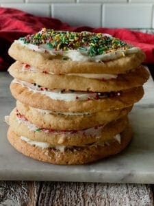 A stack of frosted sugar cookies with sprinkles.