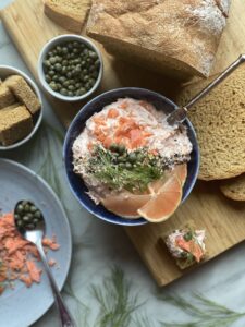 Smoked salmon spread in a bowl with capers on top and bread on the side