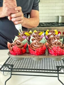 chocolate cupcakes being frosted by a man