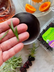 Driscolls blackberries, and hand with rosemary in it