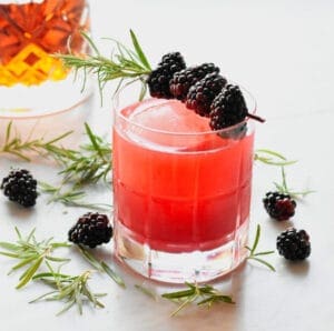 Blackberry and rosemary garnished Bourbon sour with bourbon