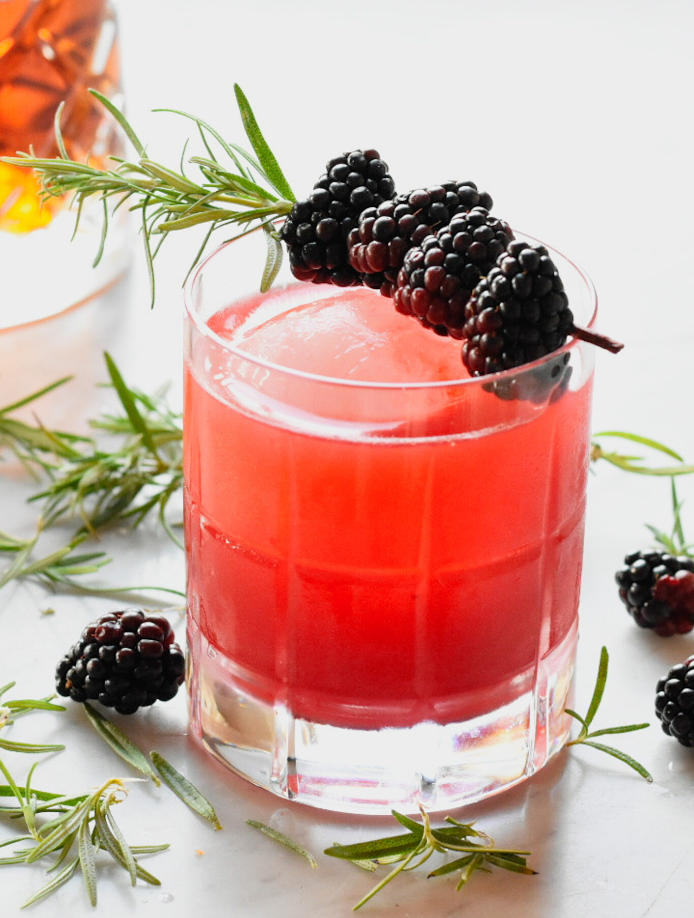 Blackberry bourbon sour in a glass with rosemary and blackberry garnish
