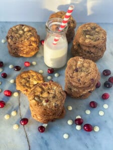 Stacks of cranberry white chocolate chip cookies with bottle of milk and red and white straw