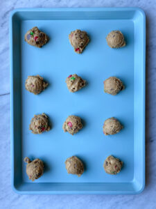 Chocolate chip M&M cookie dough on a blue cookie pan