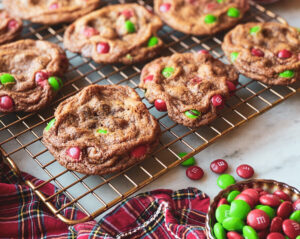 M&Ms in a bowl, plaid napkin, red and white ornament and chocolate chip cookies