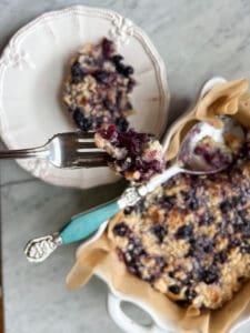Blueberry kuchen served with a large spoon on a plate with a fork