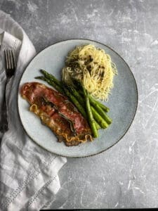 Veal Saltimbocca on a plate with angel hair and asparagus