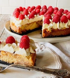Raspberry Swirl Cheesecake with Chocolate Crust with a slice cut out on a white plate with a fork