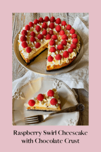 Raspberry swirl cheesecake with whipped cream and raspberries and a slice cut out on a white plate with a fork.