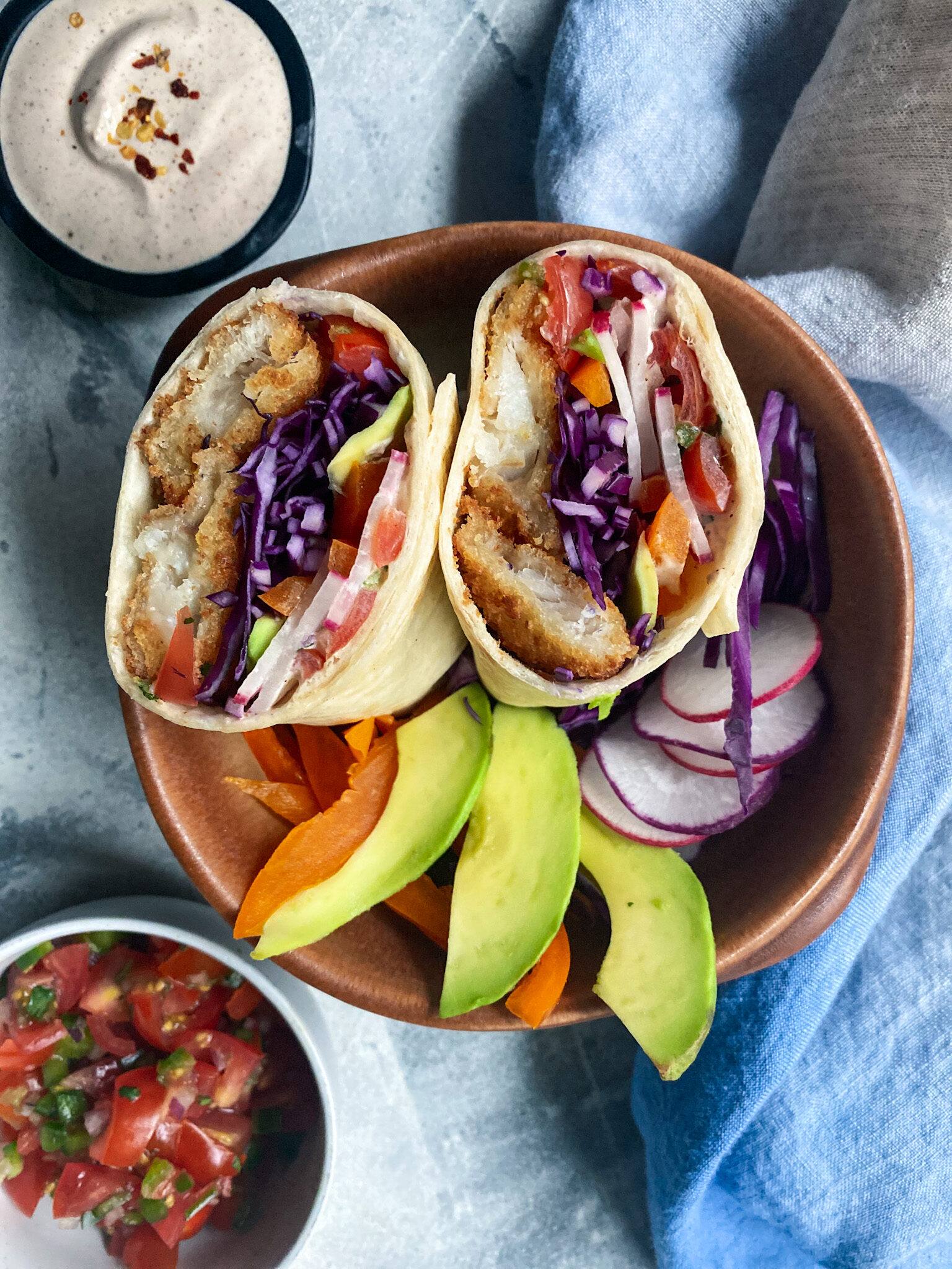 baja fish buritto cut in half in a bowl with avocado