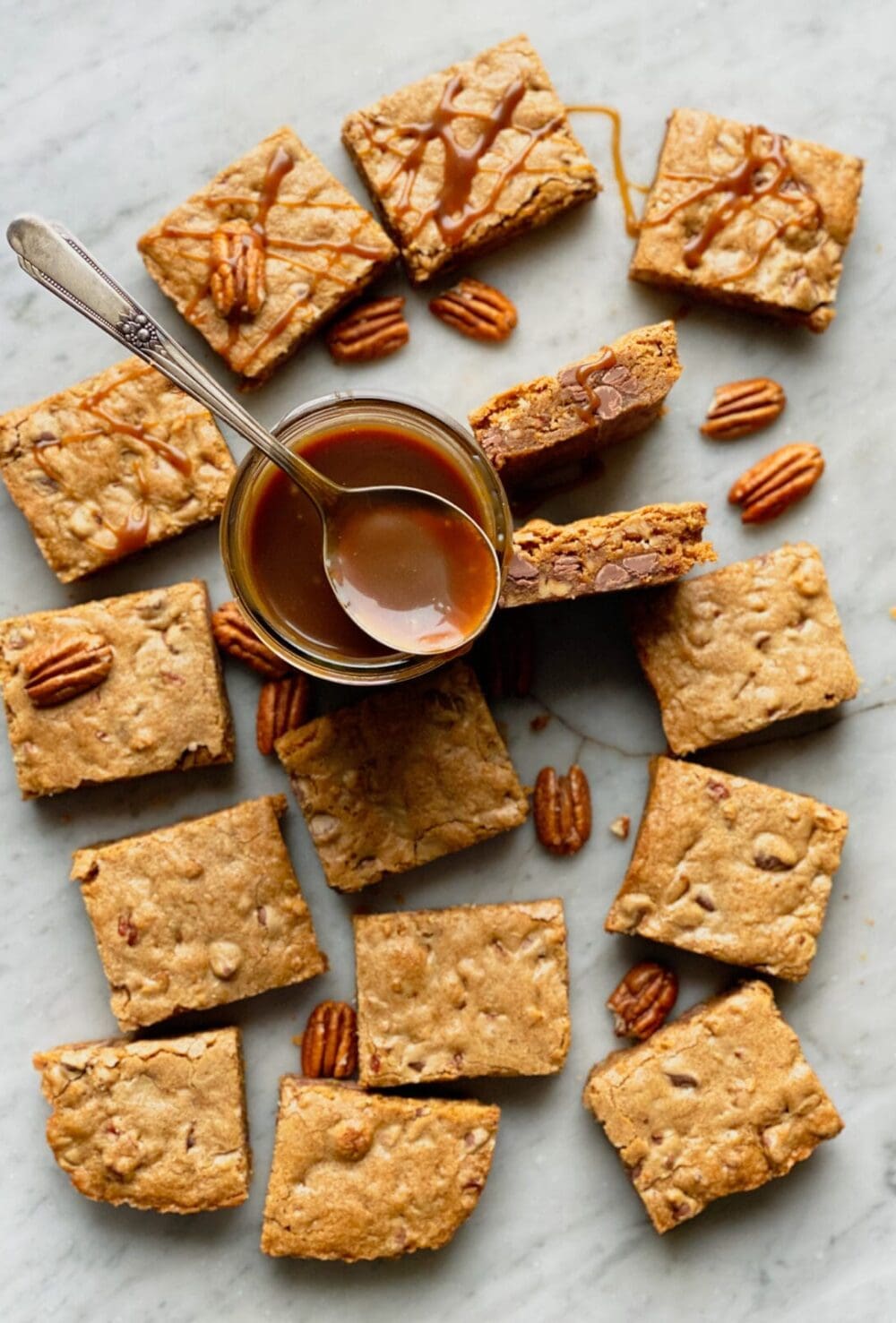 Bourbon Pecan brownie blondies and pecans on marble with salted caramel in a jar