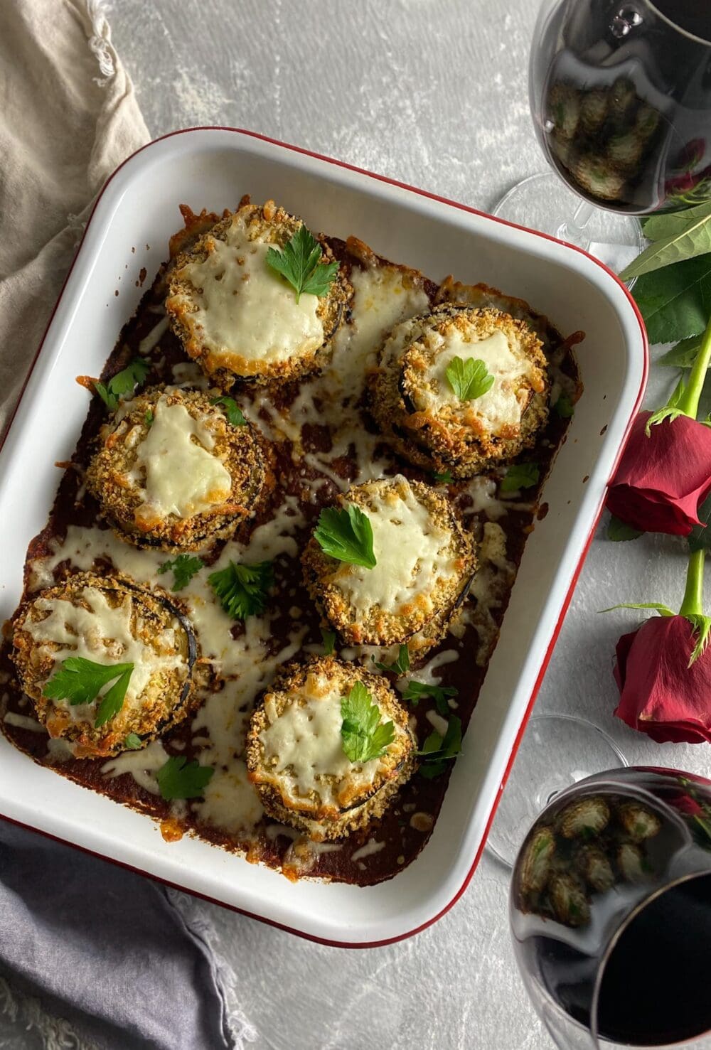 Crispy Baked Eggplant Parmesan in a pan with roses and red wine