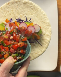 Pico di gallo being added to baja fish burrito