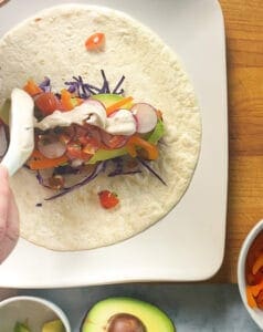 Baja sauce being added to the baja fish burrito