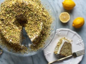 Lemon Pistachio bundt cake with a slice on a plate and lemons