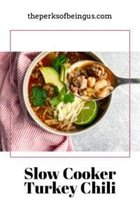 Turkey chili with avocado and cheese and lime and a spoon with chili in it