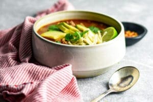 Bowl of chicken chili with avocado lime, cheese and cilantro