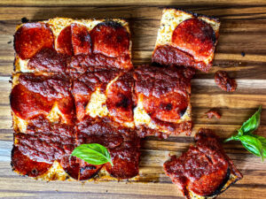 Detroit pepperoni pizza on a cutting board with basil made with Trader Joe's Pizza Dough