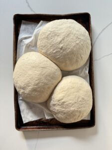 3 balls of pizza dough after they have raised overnight in the fridge