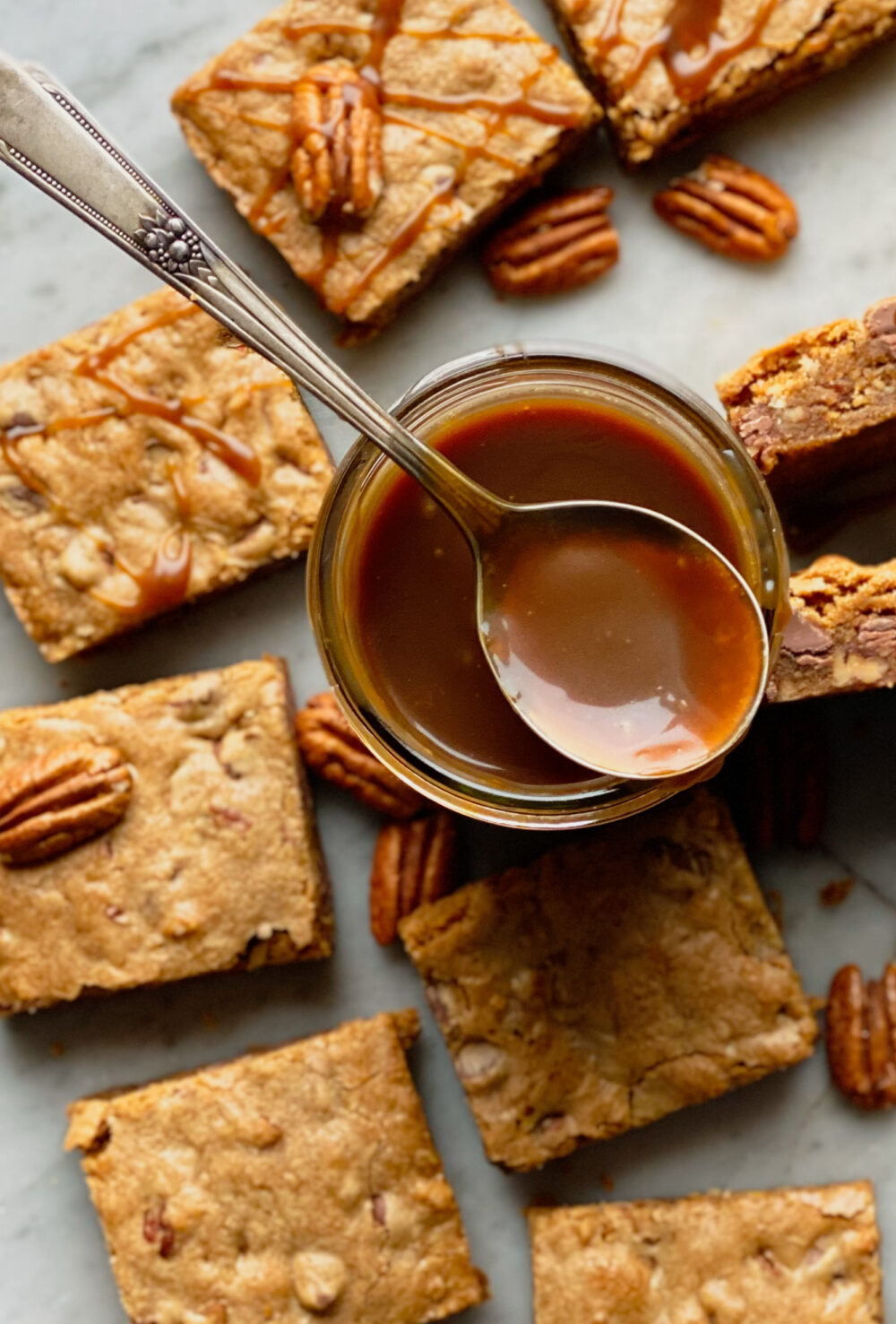 bourbon caramel sauce in a jar with a spoon and pecan blondies