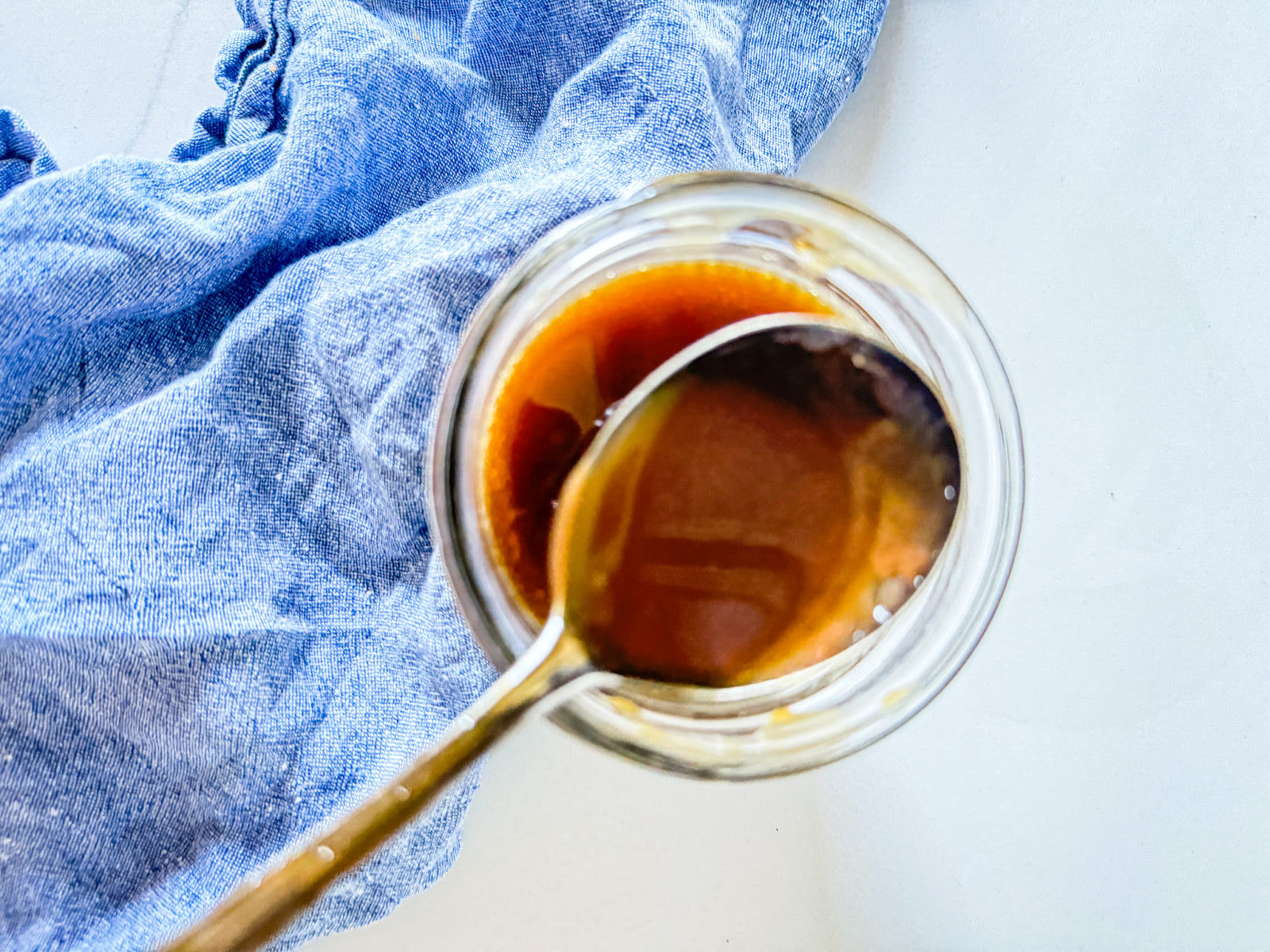 bourbon caramel sauce in a jar with a spoon and a blue napkin