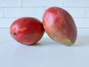 2 red skinned mangos on a counter