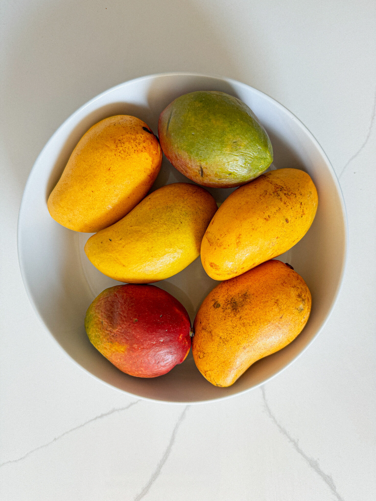 6 mangos in a bowl.