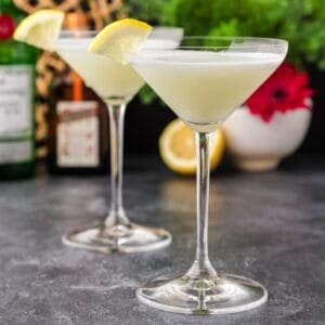 2 White lady martinis with lemon wedges and christmas decorations in backround