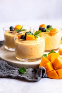 3 containers of mango mouse with fruit on top with mint