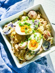 potato salad in a square bowl with eggs on top