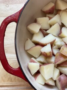 cooked red skin potatoes with skin on quartered in a red pan with white lining