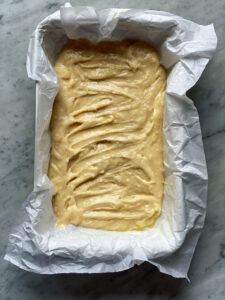 Cake batter in parchment in white pan