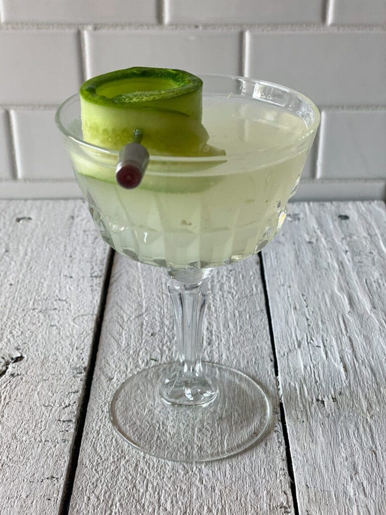 Cucumber martini in a martini glass with a curled cucumber slice for garish