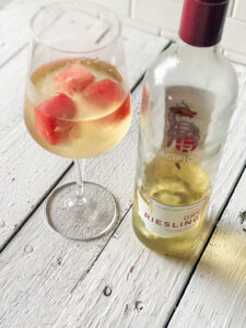 white wine in a glass with watermelon ice cubes and a bottle of white wine