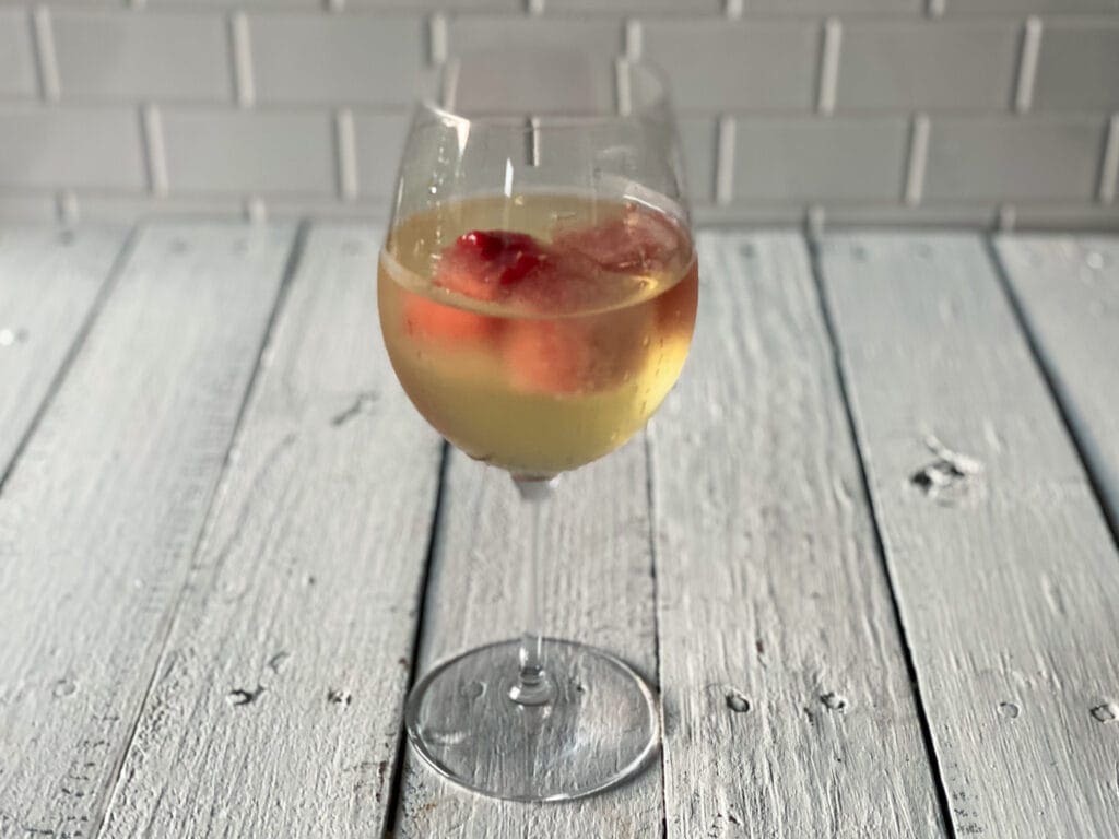 Watermelon ice cubes in a glass of white wine