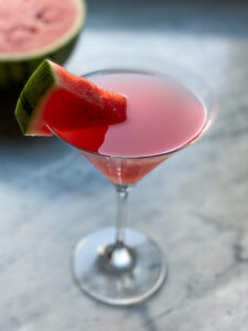 watermelon martini with a watermelon wedge and a watermelon in background