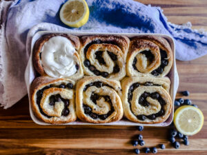 a pan of blueberry sweet rolls with lemons and blueberries and a napkin