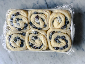 raised blueberry sweet rolls that have not been baked with plastic wrap