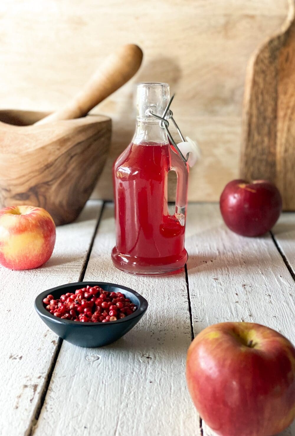 pink peppercorn syrup and apples and a mortar and pistol and pink peppercorn syrup