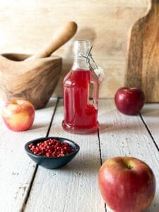 pink peppercorn syrup and apples and a mortar and pistol and pink peppercorn syrup