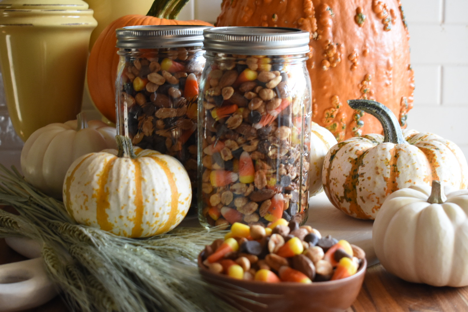 Halloween Snack mix in mason jars and a bowl with pumpkins