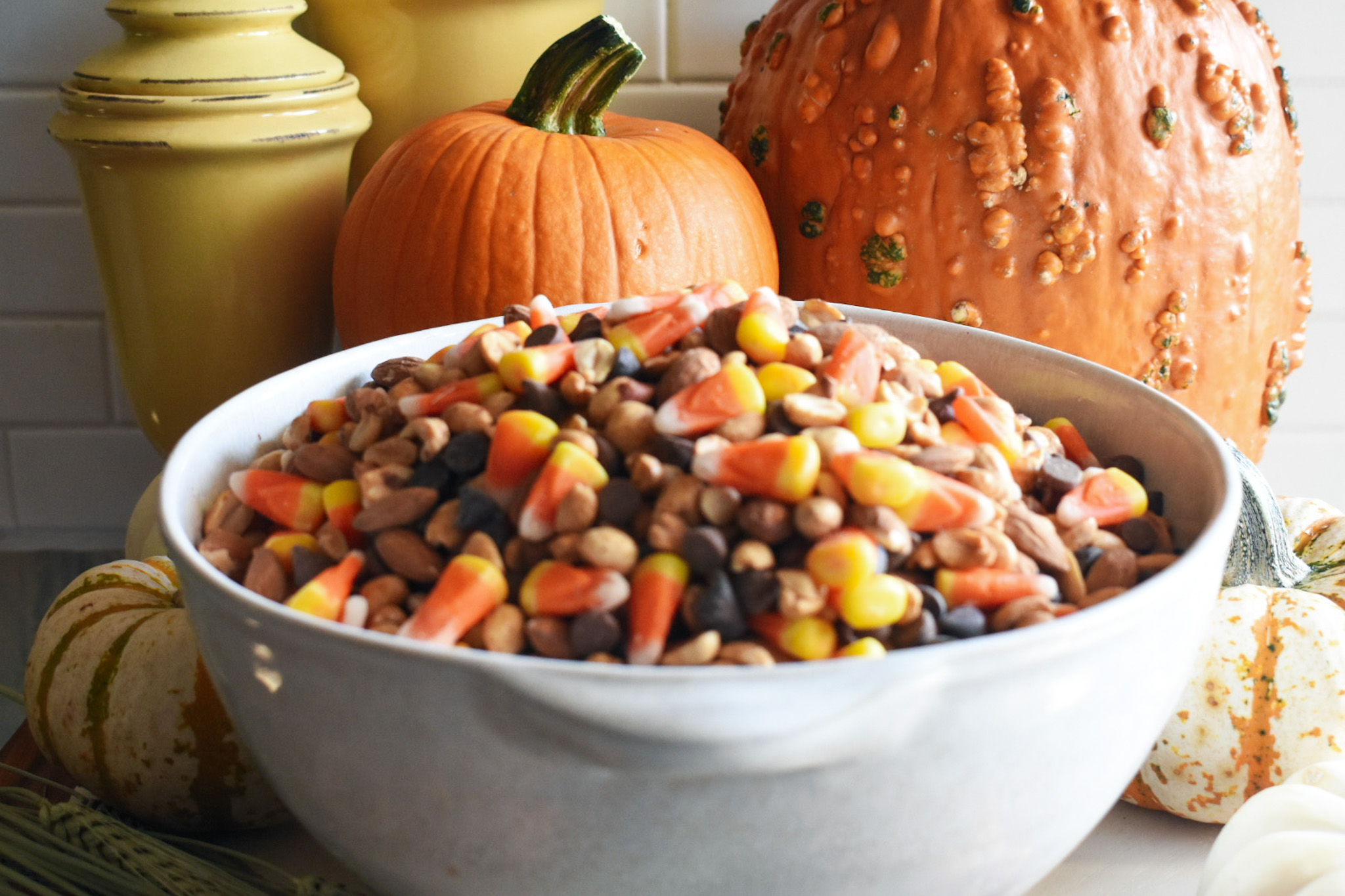 Candy corn halloween snack mix in a large bowl with pumpkins