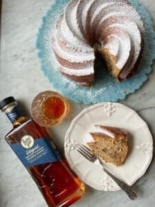 butter pecan boutbon pound cake with a glass and bottle of bourbon and slice of cake