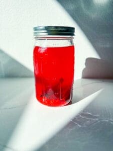 a mason jar of homemade fireball with cinnamon sticks
