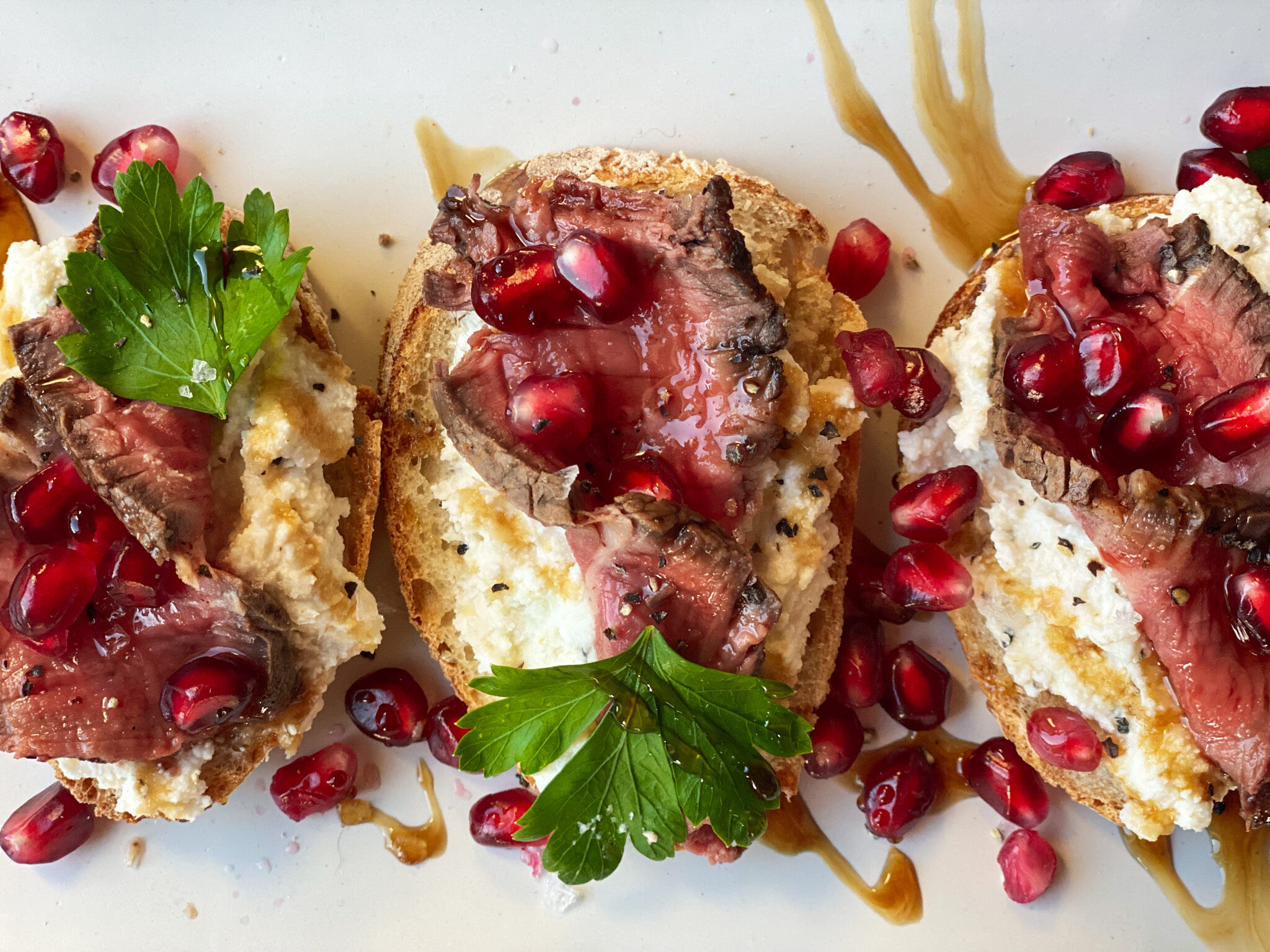 steak crostini with balsamic glaze, parsley and pomegranate