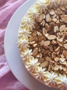 half view of amaretto cheesecake on a plate with a pink background