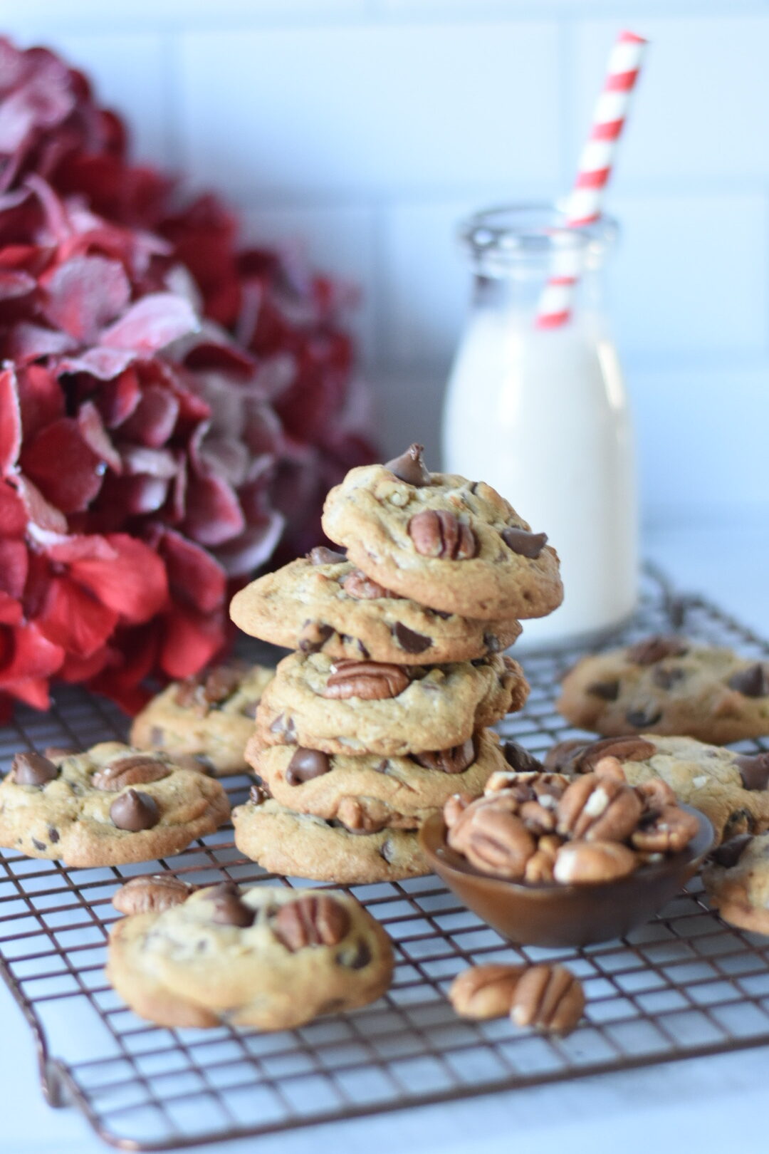 Stack of pecan chocolate chip cookies with a bottle of milk with a red and white straw